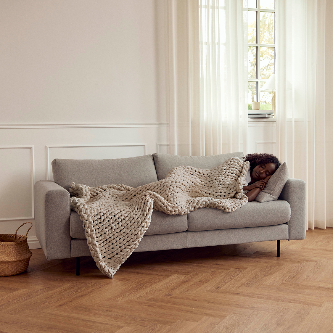 Person lying on a grey sofa with a AURTRS driftwood ocean napper