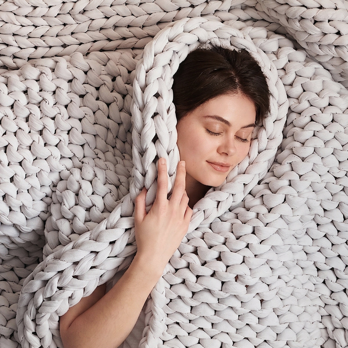Person wrapped in a moonstone grey cotton weighted blanket