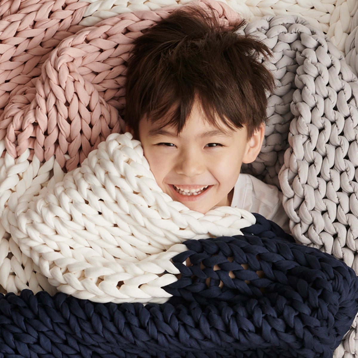 Child wrapped in a AURTRS confetti knitted blanket